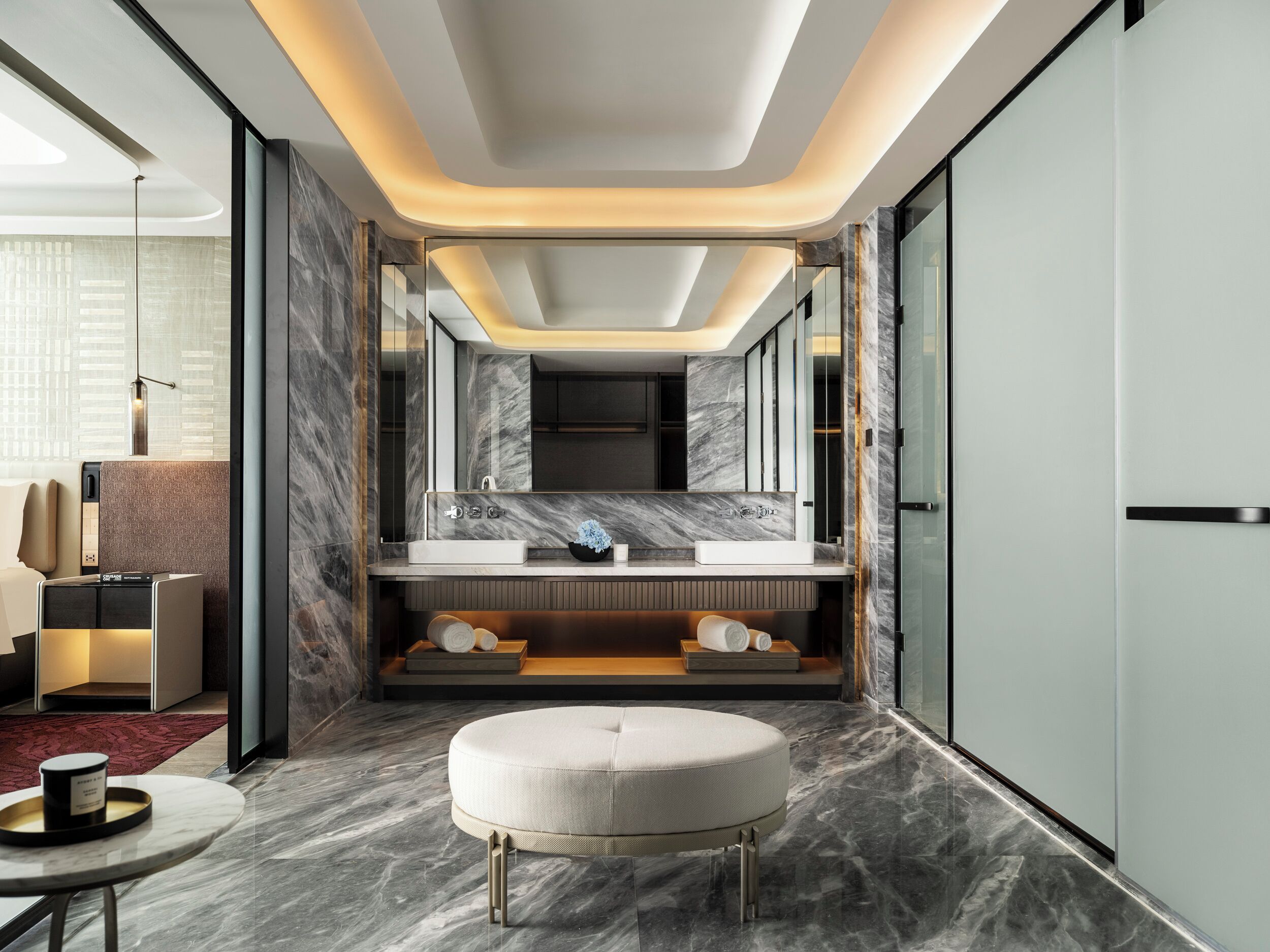 Een moderne badkamer met een grote spiegel, marmeren vloeren en een rond zitgedeelte.