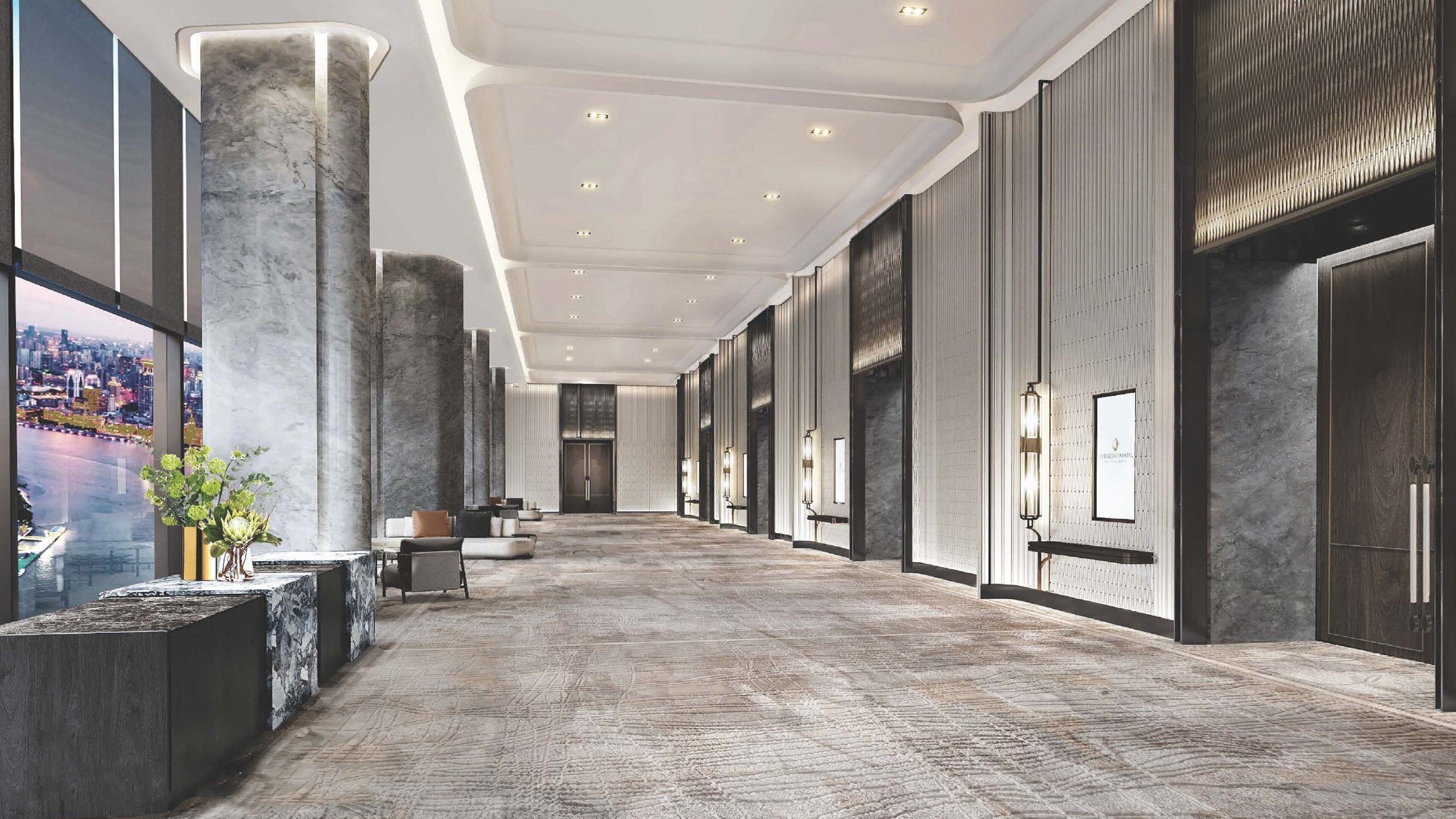 A spacious hallway with marble columns, a reception desk, and a city view.