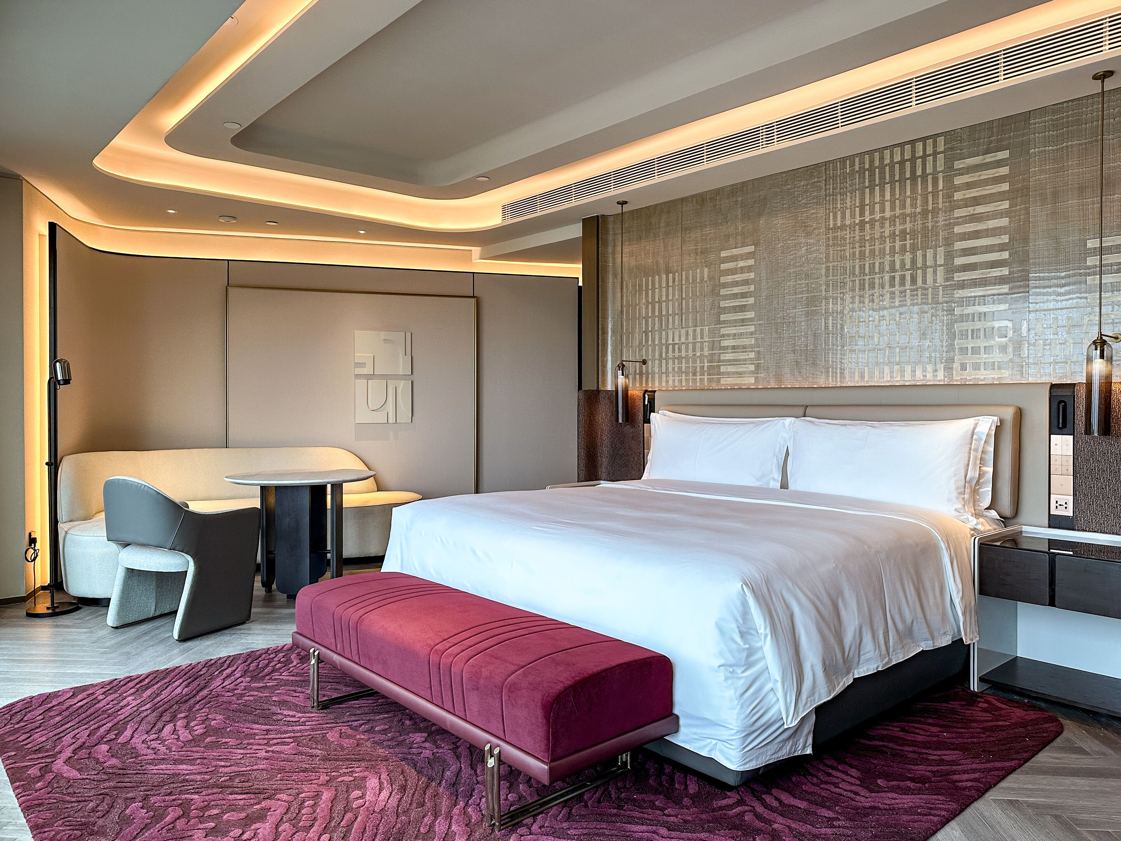 Una habitación de hotel moderna con una cama grande, un escritorio y una zona de estar.
