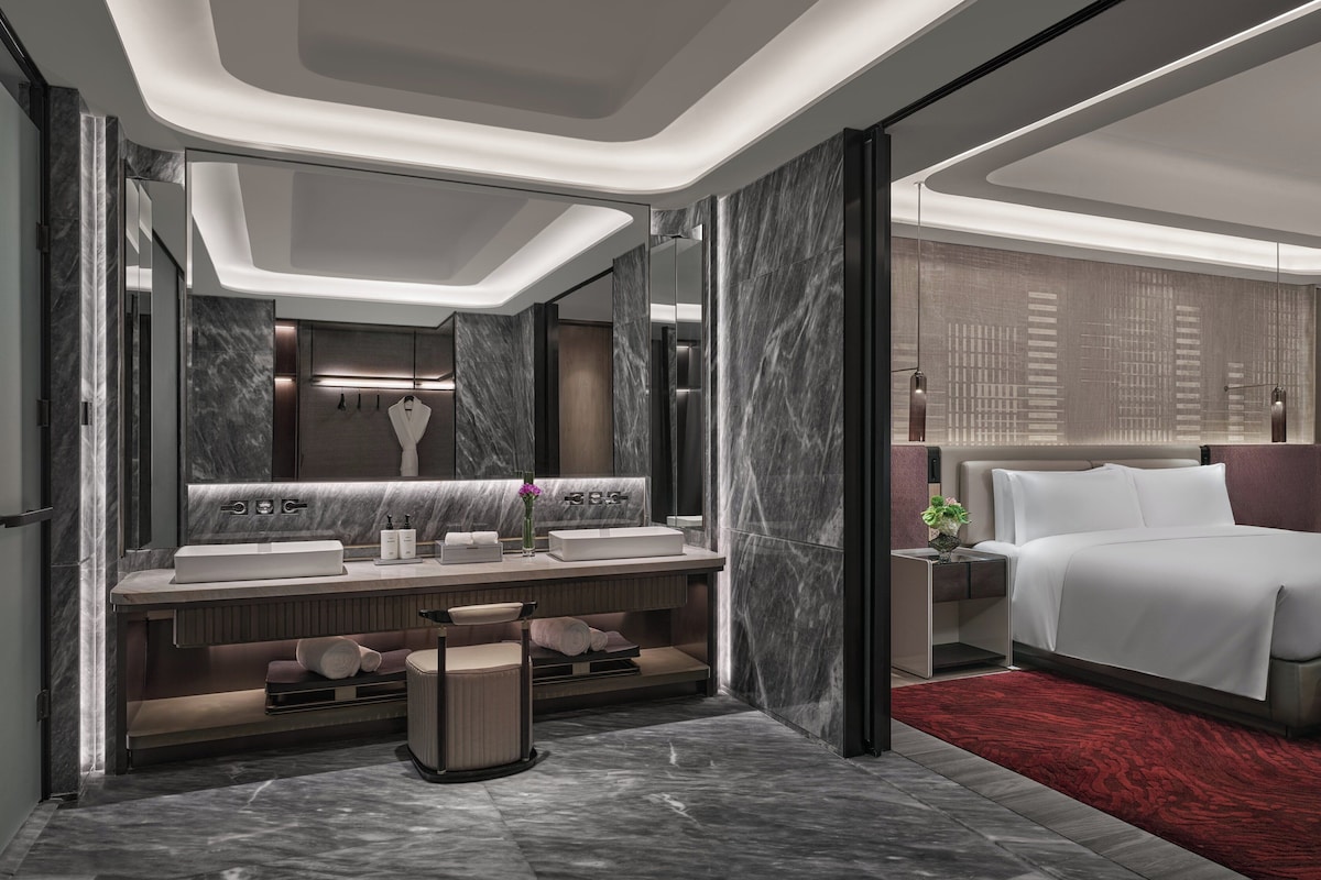 A modern hotel bathroom with a large vanity, dual sinks, and a mirror.