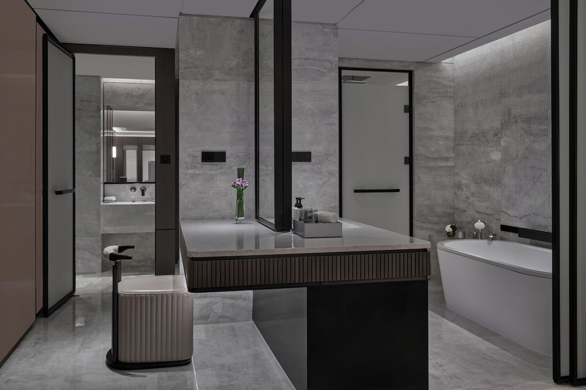 A modern bathroom with a large mirror, a vanity with a sink, and a bathtub.