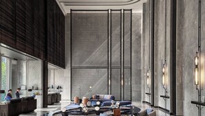 Un vestíbulo moderno con una recepción, área de estar y elementos decorativos como una fuente de agua y paneles de pared.