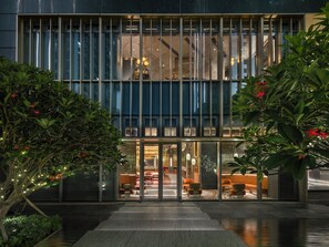 A modern building with a glass facade, a central entrance with glass doors, and indoor seating areas visible through the glass. - InterContinental Shenzhen WECC by IHG (Shenzhen)