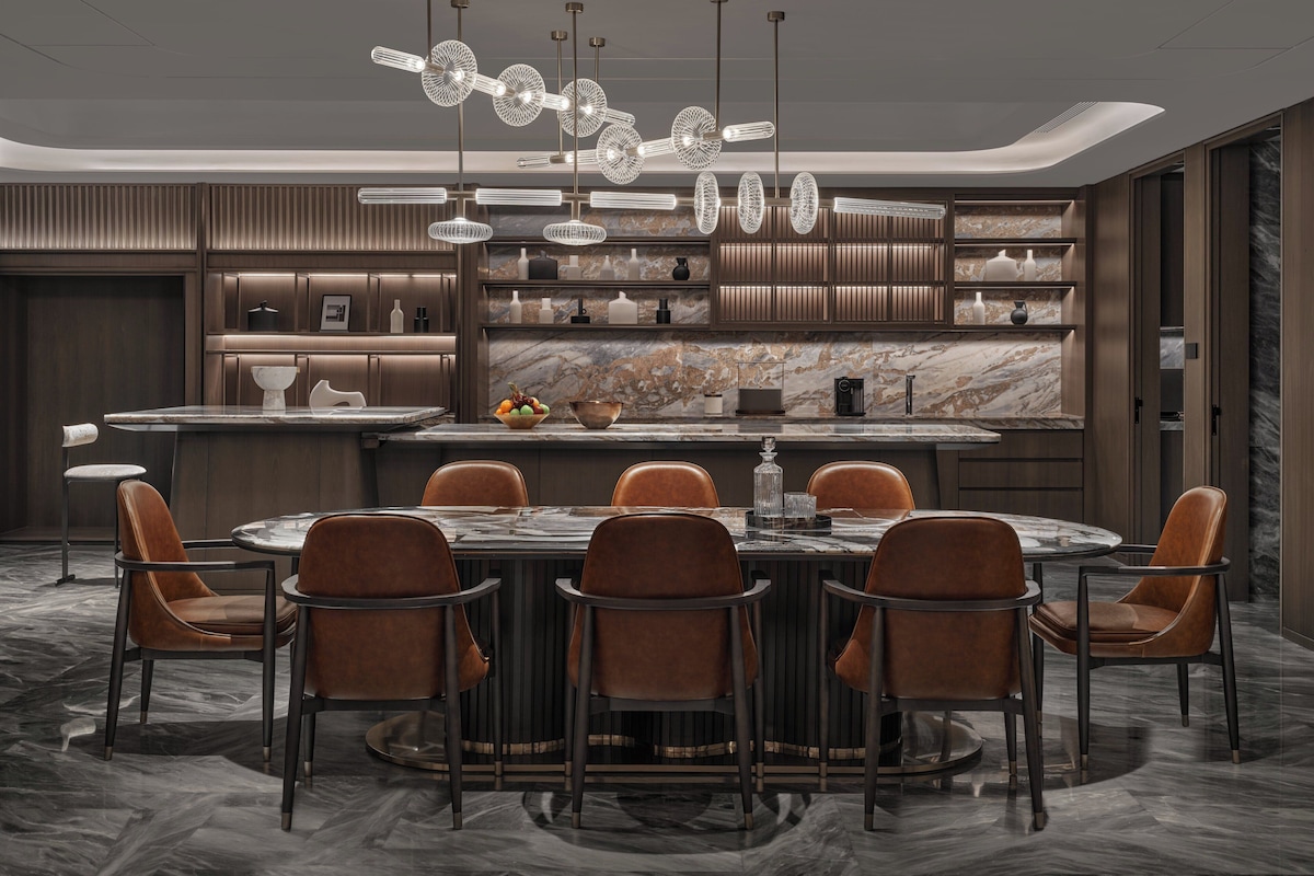 A modern dining area with a marble countertop, brown leather chairs, and a central island.