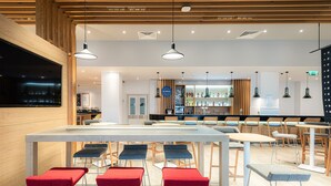Um restaurante moderno com área de bar, teto de madeira e diversas opções de assento, incluindo banquetas e cadeiras.