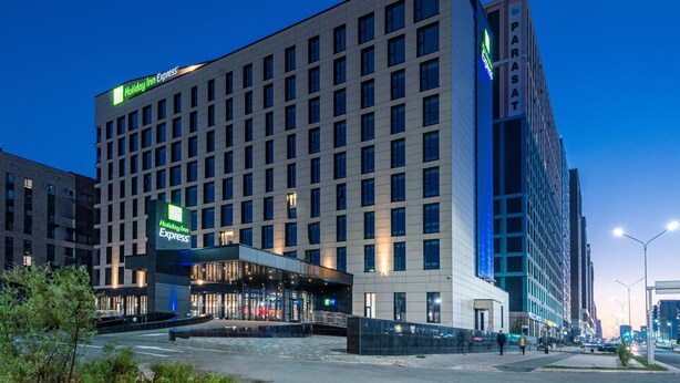 Um hotel Holiday Inn Express com fachada moderna, grandes janelas e entrada destacada.