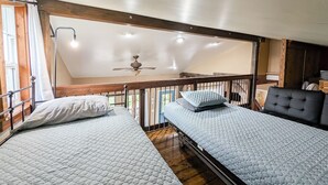Une chambre de dortoir avec deux lits simples, un ventilateur de plafond et une vue sur l’extérieur.