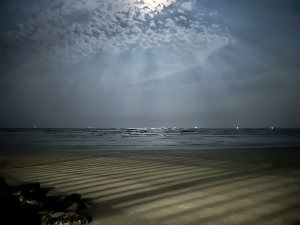 Une plage avec une mer calme et un ciel nuageux.