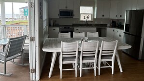A modern kitchen with white cabinets, a stainless steel refrigerator, and a dining area with a wooden table and chairs. - Short walk to the beach (Freeport)
