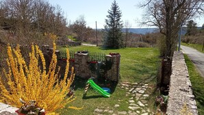 Ein Garten mit einer Steinmauer, einer Schaukel und verschiedenen Blumentöpfen.