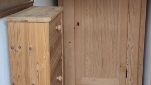 Una habitación con un armario de madera, un espejo y suelo de baldosas.