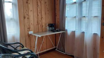 Ein kleines Zimmer mit Holzwänden, einem Tisch mit Kaffeemaschine und zwei Stühlen.