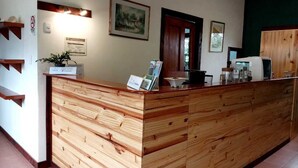 Un comptoir d’accueil avec un revêtement en bois, une plante, des certificats encadrés et une porte en arrière-plan.