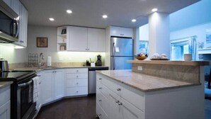 A modern kitchen with white cabinets, a stainless steel refrigerator, and a built-in oven. - Sun Valley/Ketchum-Location, Hot tub, pet friendly, walk to ski and downtown (Ketchum)