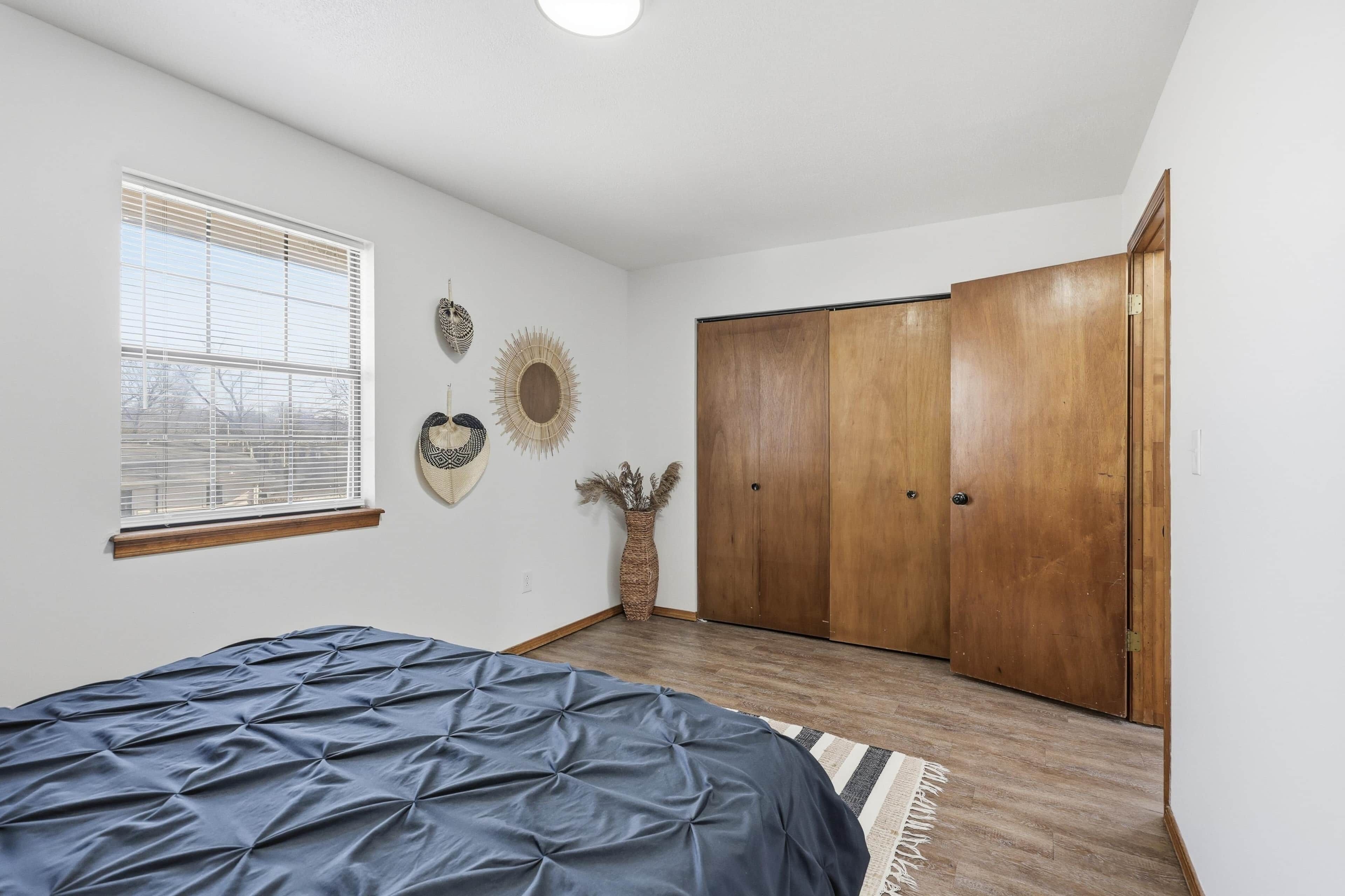 Een slaapkamer met een bed, een raam, een kledingkast en decoratieve wandpanelen.