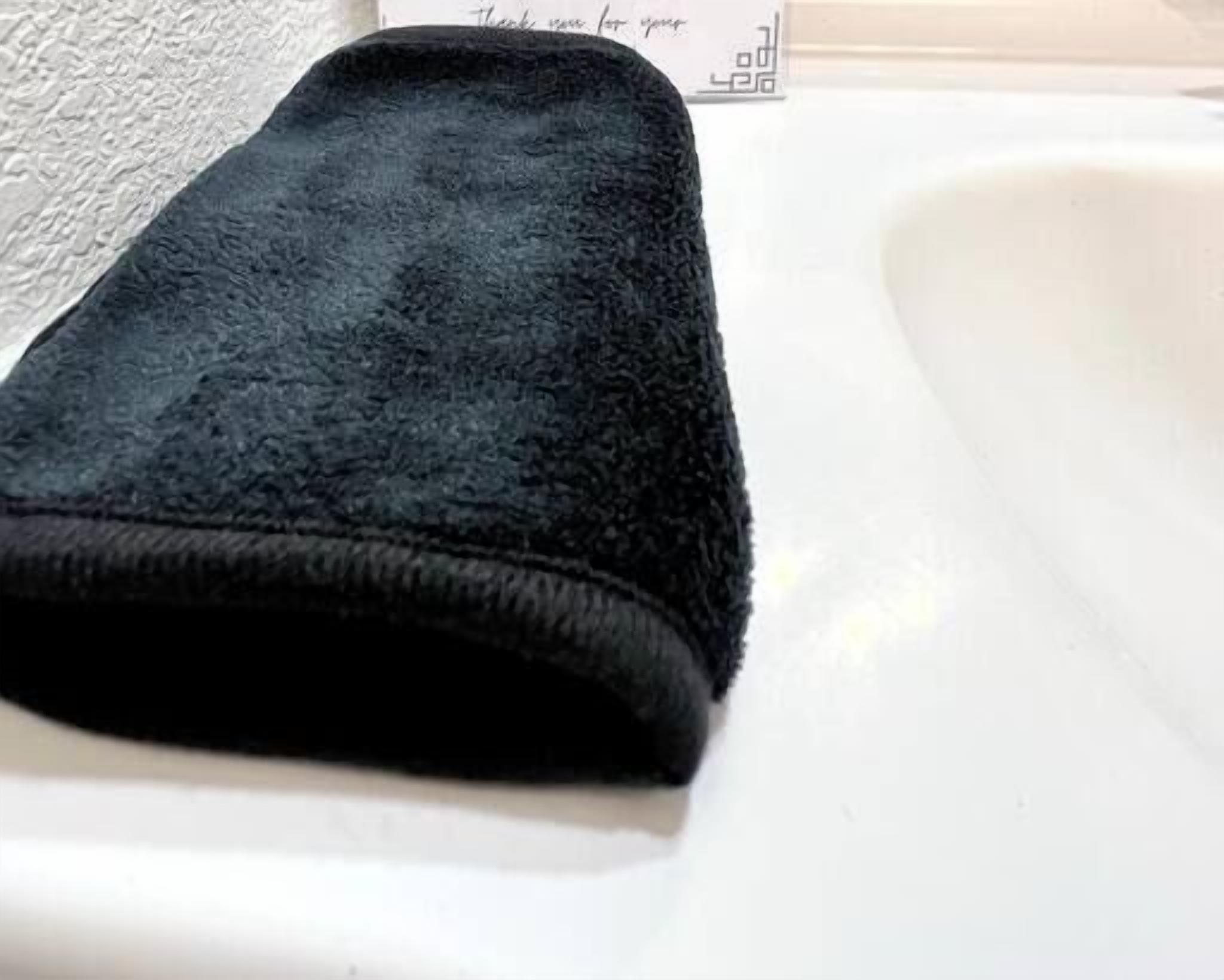 Ein schwarzes Handtuch auf einem weißen Waschbecken.