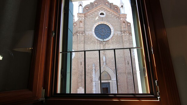 A window with a view of a brick building with a circular window and a statue. - Frari Prestige Canal View (Historical Center) (Venecia)