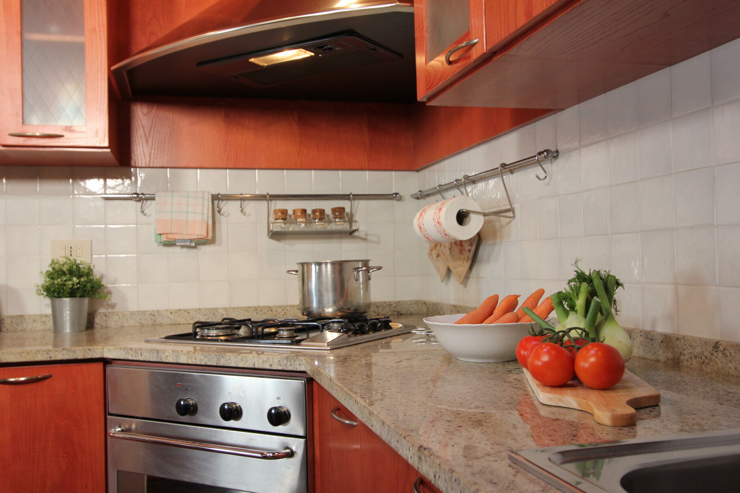 Une cuisine avec des meubles en bois, une cuisinière en acier inoxydable et un plan de travail en granit.