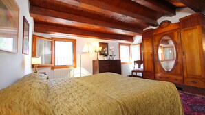 A bedroom with a large bed, wooden ceiling beams, a dresser, a mirror, and a window with a view. - Frari Prestige Canal View (Historical Center) (Venecia)