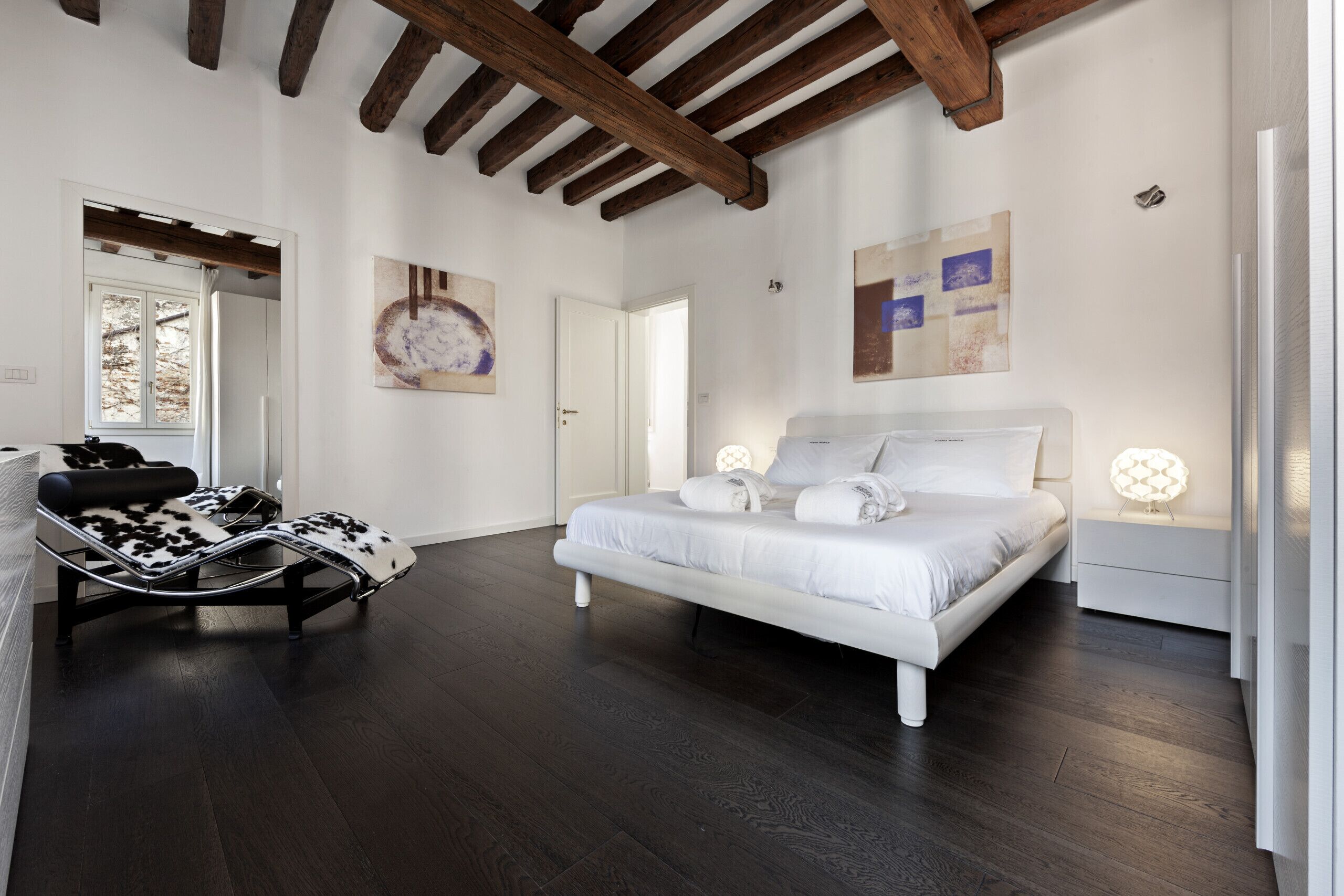 A bedroom with a bed, a chair, and a nightstand.