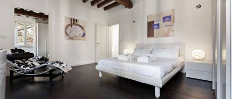 A bedroom with a bed, a chair, and a nightstand.