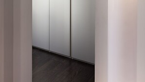Un intérieur moderne au design minimaliste, avec une armoire blanche, un plancher en bois et un luminaire fixé au mur.