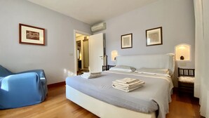 Una habitación de hotel con una cama grande, una silla y una puerta que da a un baño.