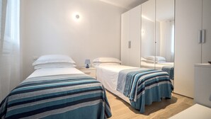 Una habitació d'hotel moderna amb dos llits individuals, un mirall gran i un armari.