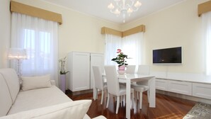 A modern living room with a sofa, dining table, chairs, a TV, and a chandelier. - Apt. Splendid Venice (250m from St. Mark´s Square) (Venecia)