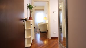 A hallway with a wooden floor, a potted plant, a white chair, and a mirror on the wall. - Apt. Splendid Venice (250m from St. Mark´s Square) (Venecia)