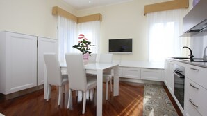 A modern kitchen with white cabinets, a dining table with chairs, a TV, and a small oven. - Apt. Splendid Venice (250m from St. Mark´s Square) (Venecia)