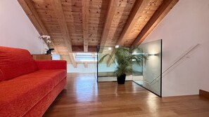 A modern interior with a wooden ceiling, a red sofa, a potted plant, and a glass partition. - Apartment Baia (Historical Center) (Venecia)