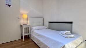 A single bed with a headboard, a bedside table with a lamp, and a folded towel on the bed. - Apartment Baia (Historical Center) (Venecia)