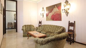 A living room with a green patterned sofa, a wooden coffee table, and two wall-mounted lamps. - Corner Canal View (300m from Rialto´s Bridge) (Venecia)