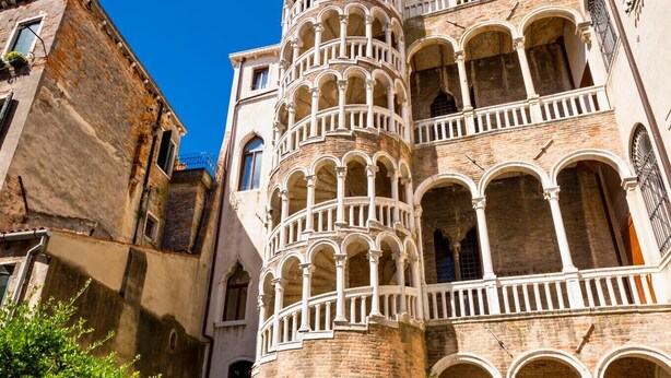Um edifício histórico com uma torre imponente, com várias varandas e janelas em arco.