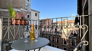 Uma varanda com uma mesa, duas taças de vinho e uma garrafa de vinho.