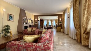 Uma sala de estar ampla com lareira, área de jantar e vista para a sala de jantar através de uma porta.