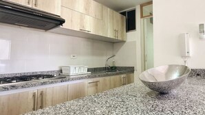A kitchen with granite countertops, wooden cabinets, a stainless steel sink, and a built-in stove. - 207 AKUA RESORT® VACATION APARTMENT (Ricaurte)