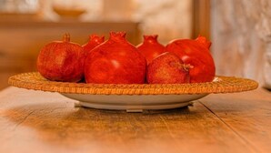 A pomegranate on a plate on a table in a room with a stone wall and a lamp in the background. - Macchiaroli La Gioiosa Castle the magic of a medieval castle in Teggiano (Teggiano)