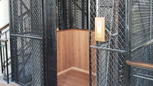 A small, enclosed elevator area with a wooden interior and metal mesh walls. - Gran Hotel Alijadores (Tampico)