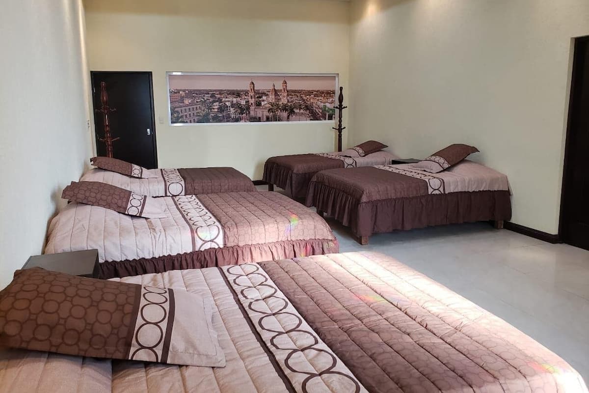 A bedroom with three beds, a cityscape view, and a laptop on the floor.