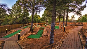 A miniature golf course with multiple holes, surrounded by trees and a wooden fence. - 1Bed/1Bath - Gorgeous Flagstaff with Pools, Golf, and More! (Flagstaff)