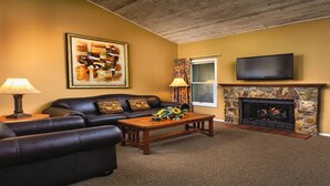 A living room with a fireplace, a sofa, a coffee table, and a television. - 1Bed/1Bath - Gorgeous Flagstaff with Pools, Golf, and More! (Flagstaff)