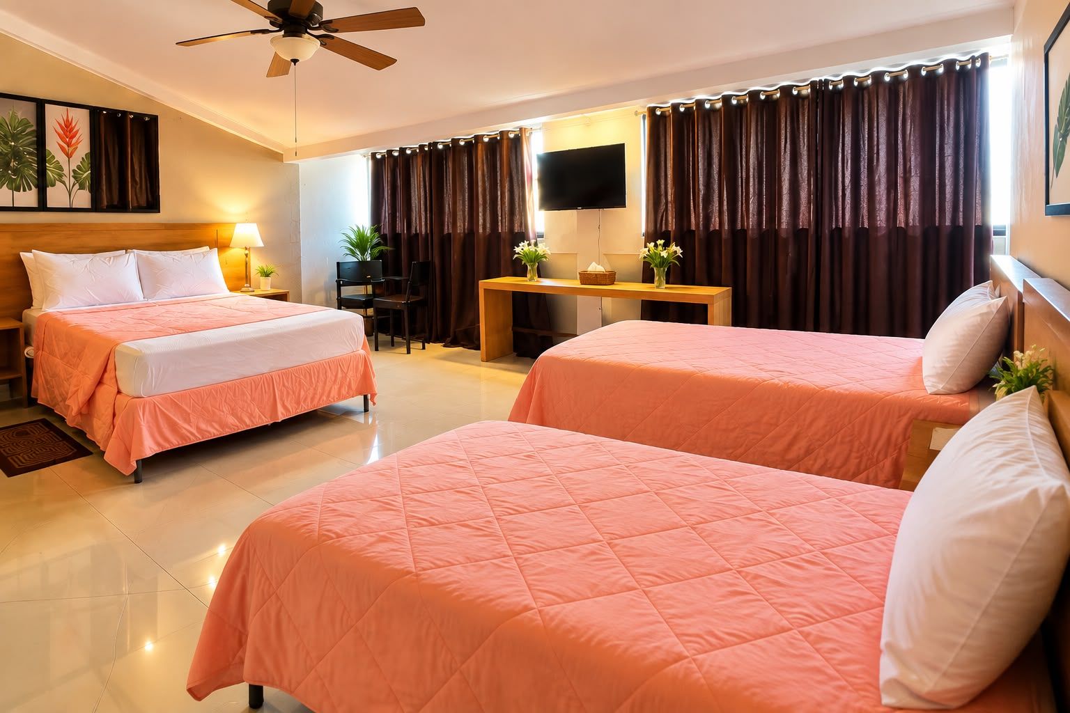 A hotel room with two beds, a desk, a chair, a television, and a ceiling fan.