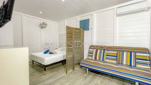 Een kamer met een bed, een bank, een ventilator en een raam met gordijn.