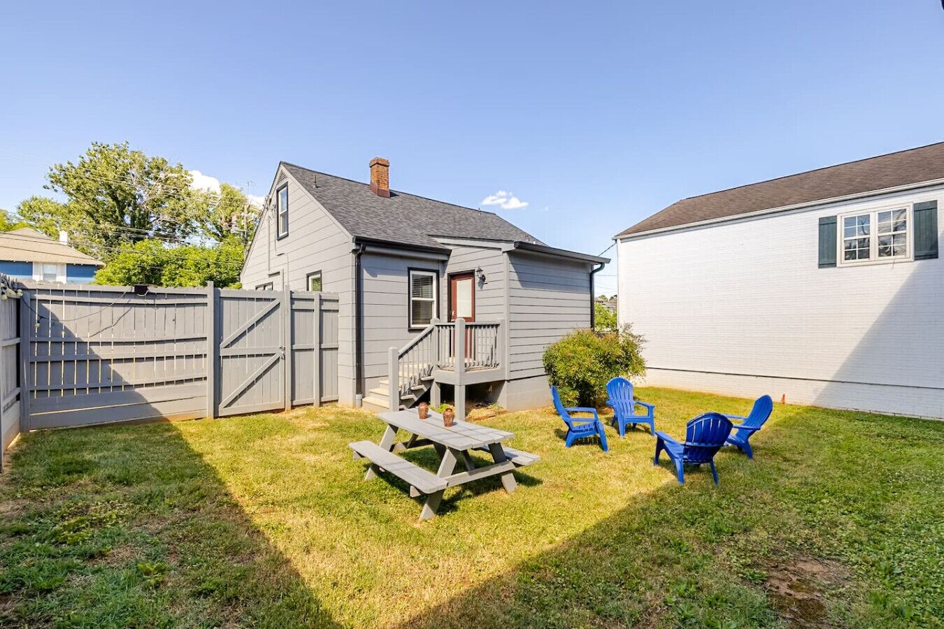 Un jardin avec une terrasse en bois, une table de pique-nique et des chaises bleues.