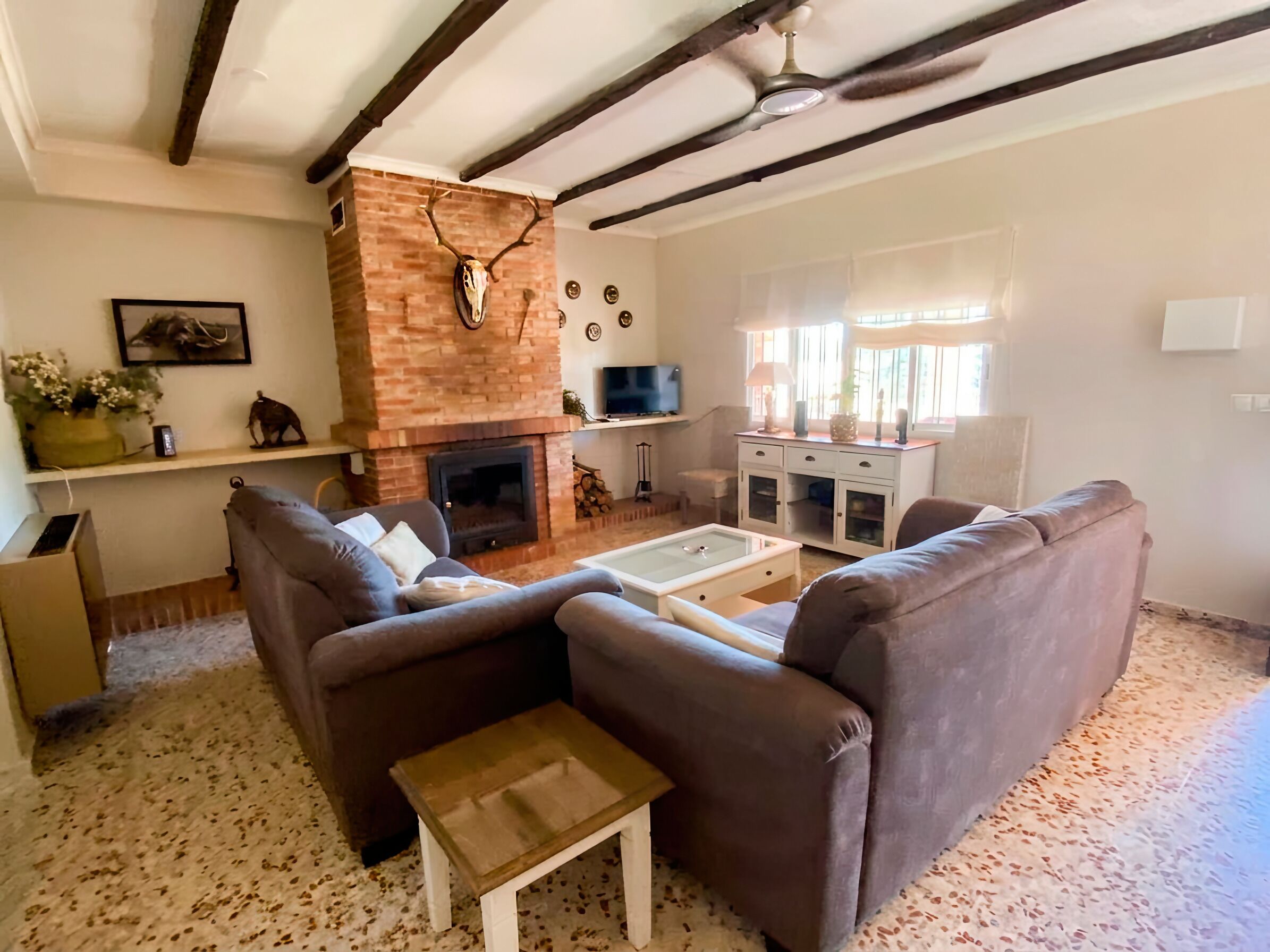 A living room with a fireplace, a sofa, a coffee table, and a television.