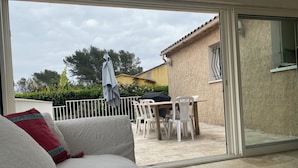 Een kamer met een schuifdeur die uitkomt op een buitenpatio met een tafel en stoelen.