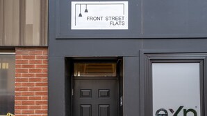 Een gebouw met een bord waarop 'Front Street Flats' staat en een deur met de aanduiding 'exp Realty Brokerage'.