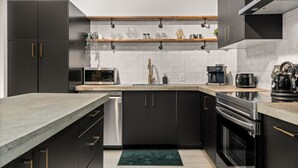 Een moderne keuken met donkere kastjes, een houten aanrechtblad en roestvrijstalen apparatuur.
